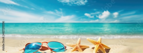 Beautiful colorful background for summer beach holiday. Sunglasses, starfish, turquoise flip-flops on sandy tropical beach against blue sky with clouds on bright sunny day.