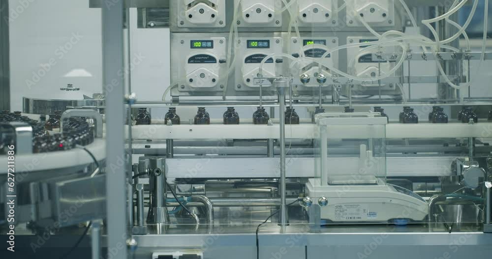 Robotic arm put medicine package on conveyor belt. Packaged goods at automated production line. Medical factory assembly line packing medicine machine. Production line of pharmaceutical manufacturing. Robotic arm put medicine package on conveyor belt. Packaged goods at automated production line. Medical factory assembly line packing medicine machine. Production line of pharmaceutical manufacturing.