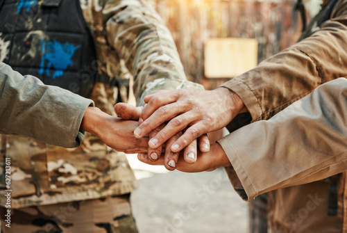 Paintball, team and hands together for meeting in motivation, huddle or game plan on the battle field. Group of paintballers piling hand for teamwork, unity or collaboration in goals, mission or war