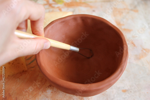 Woman's hand molding a clay bowl
