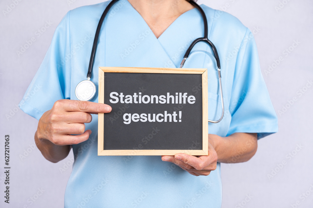 Krankenschwester oder Ärztin mit einer Tafel auf der Stationshilfe gesucht steht Krankenschwester oder Ärztin mit einer Tafel auf der Stationshilfe gesucht steht