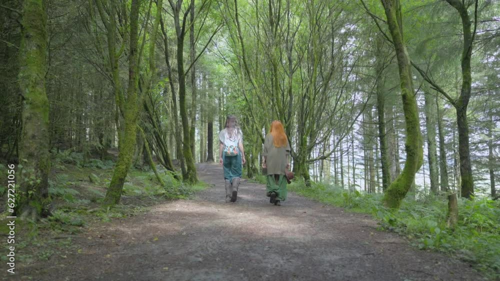 Girls walking away from camera along forest path through pools of sunlight in summer at half speed slow motion. Sony FX30. Girls walking away from camera along forest path through pools of sunlight in summer at half speed slow motion. Sony FX30.
