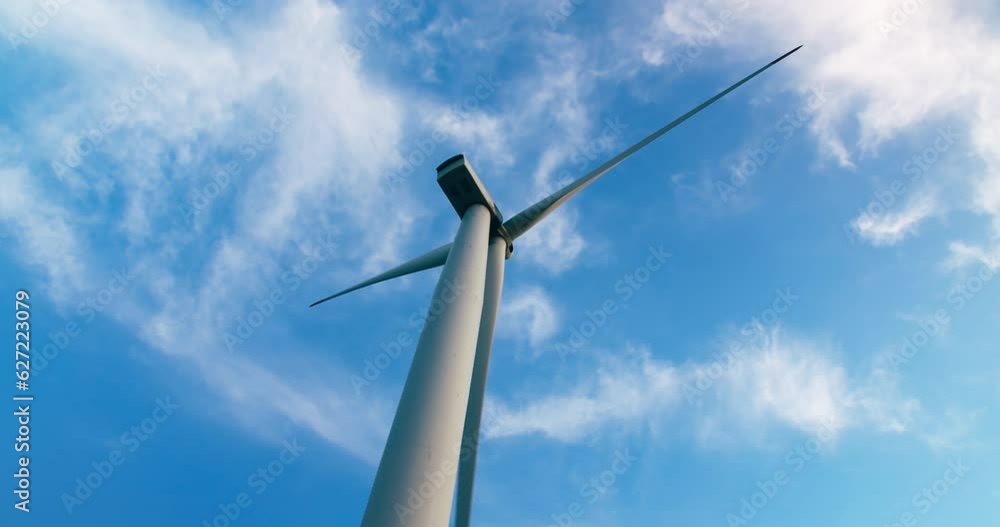 Low angle shot of wind turbine against blue sky on sunny day Low angle shot of wind turbine against blue sky on sunny day