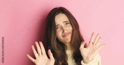 Pretentious brunette woman in knit sweater pointing fingers to camera and next laugh on pink background. Girl laughing with a grin, sarcasm, sarcastically, ask you no, not you, i not choice you! photo