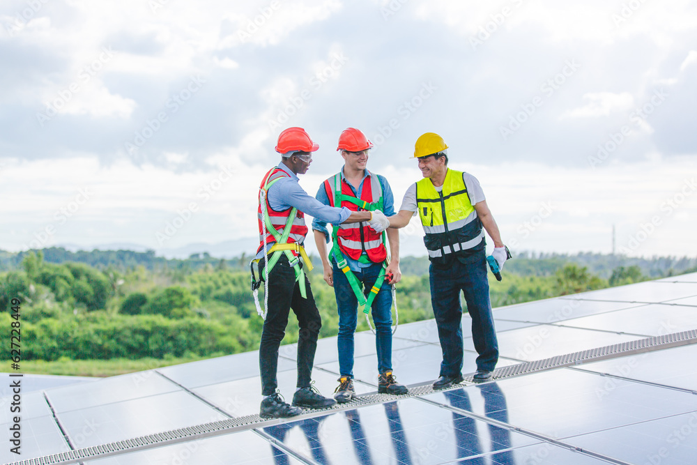 Professional technicians carrying photovoltaic solar moduls on factory roof, Engineers in helmets installing solar panel system outdoors. Concept of alternative and sustainable renewable energy.