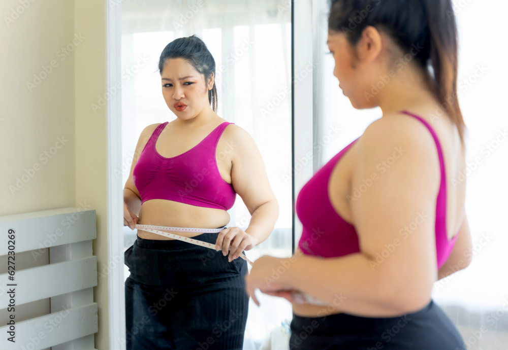 asian fat women , Fat girl , Chubby, overweight plus size looking the mirror measuring her waist in the bedroom - lifestyle Woman diet weight loss overweight problem concept