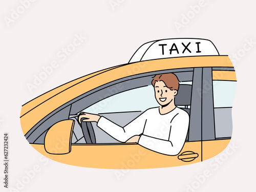 Man sits behind wheel of TAXI car and looks out window making career as public transport driver. Positive young guy TAXI driver looks at screen offering to get home quickly and safely