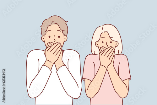 Frightened couple covers their mouths after seeing unexpected incident and looks at screen