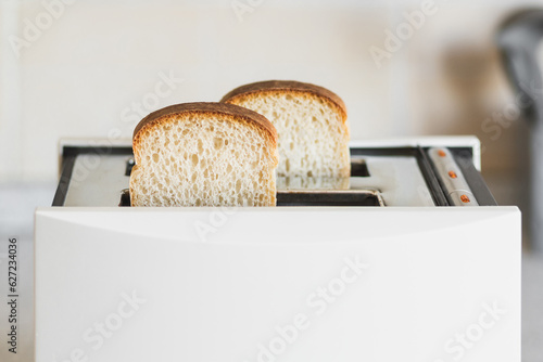 White toaster with white bread in a bright kitchen, selective soft focus, high key.
