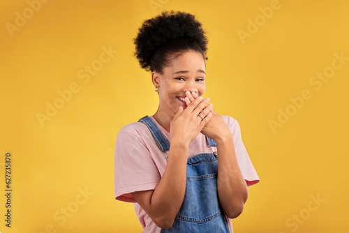 Laughing, funny and portrait of woman with wow reaction to news isolated in a yellow studio background. Comedy, comic and happy young female person covering mouth due to crazy gossip energy or meme