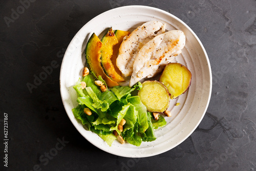 grilled chicken breast and fresh vegetable salad on white plate.