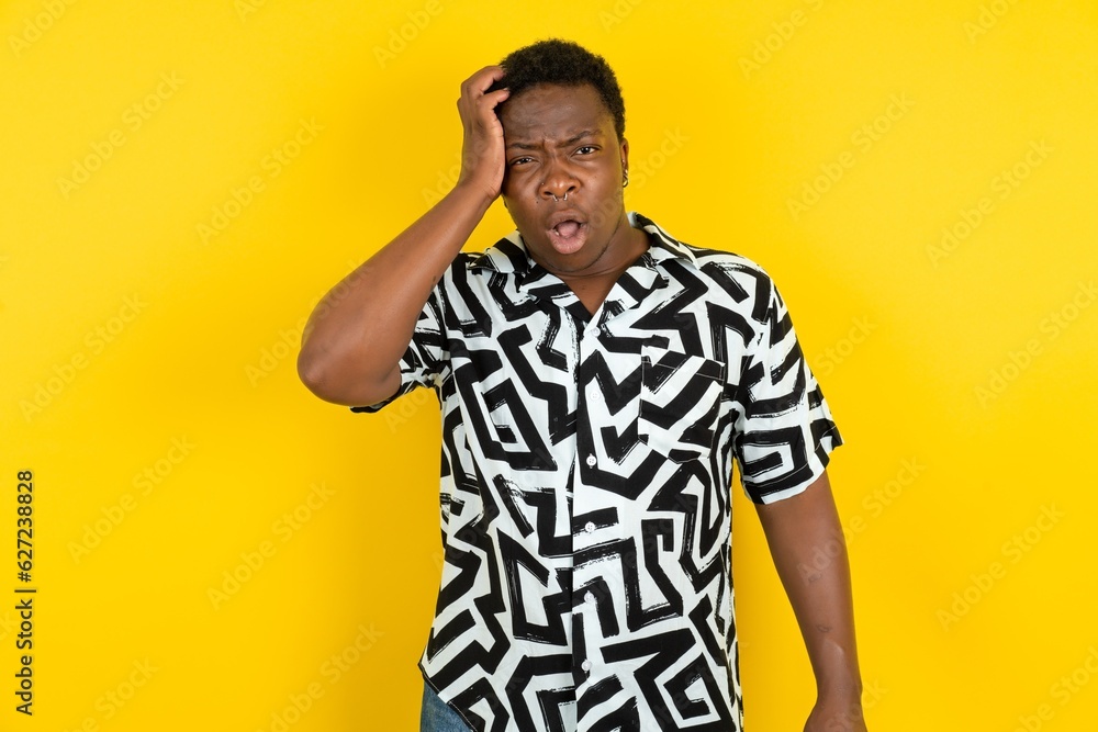 Embarrassed Young latin man wearing printed shirt over yellow background with shocked expression, expresses great amazement, Puzzled model poses indoor Embarrassed Young latin man wearing printed shirt over yellow background with shocked expression, expresses great amazement, Puzzled model poses indoor