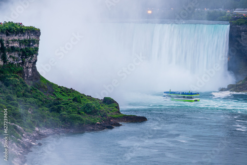 A boat with tourists heading into the mist of the Horseshoe falls in the Niagara Falls.