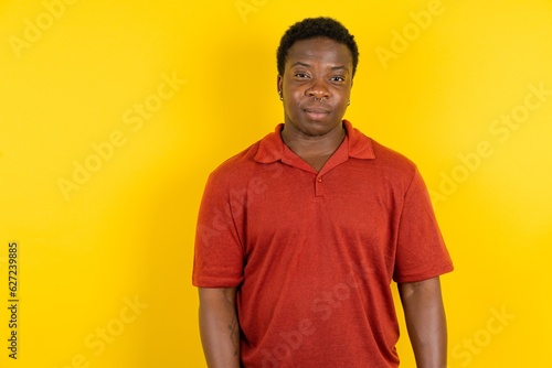Young latin man wearing red t-shirt over yellow background depressed and worry for distress, crying angry and afraid. Sad expression.