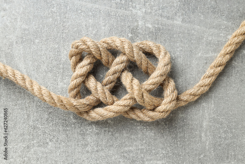Thick knotted rope close-up on gray background