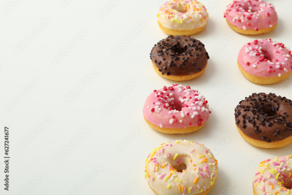 Chocolate, white and pink donuts on white background, space for text Chocolate, white and pink donuts on white background, space for text