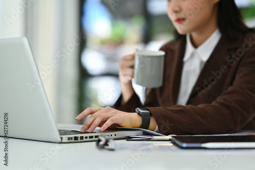 Select focused on hand of young businesswoman typing on laptop keyboard. Technology, business and communication