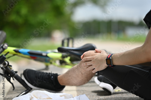 Male cyclist having an accident, falling down from bicycle and injured his knee. Bicycle accident