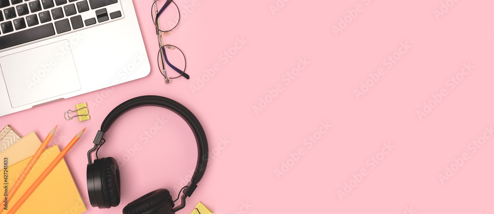 Banner with laptop, headphones and office supplies on a pink background. Workspace with place for text. Banner with laptop, headphones and office supplies on a pink background. Workspace with place for text.
