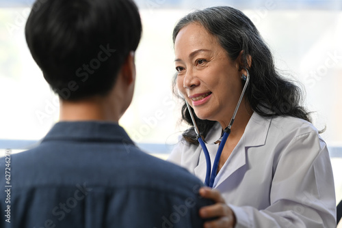 Mature doctor using stethoscope to checking heart and lungs of patient. Medical, consultation, diagnostic and health care