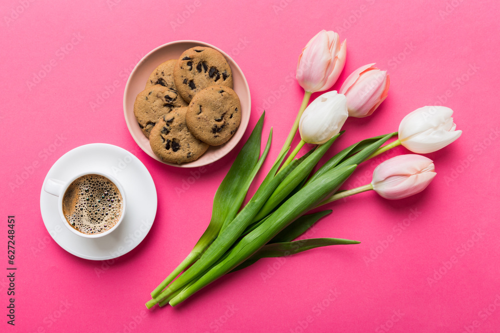 Cup of coffee mug with coffee, cookies and tulips on a colored background. Greeting spring card top view Cup of coffee mug with coffee, cookies and tulips on a colored background. Greeting spring card top view