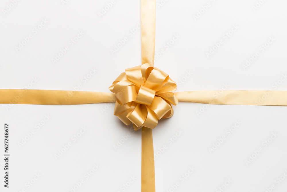Fototapeta premium Top view of gold ribbon rolled and yellow bow isolated on colored background. Flat lay with copy space