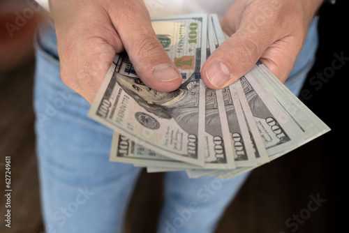 A man in a white shirt holds money, counts it and offers it to another. Close up male hand Counting and holding money us dollar. The concept of financial business and crisis.