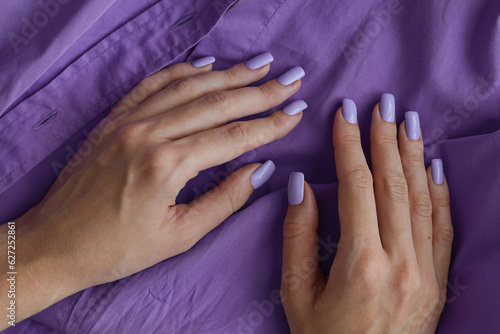 Female's hands with gelish manicure and nails of purple color. Lavender fingernails. Permanent nail polish photo