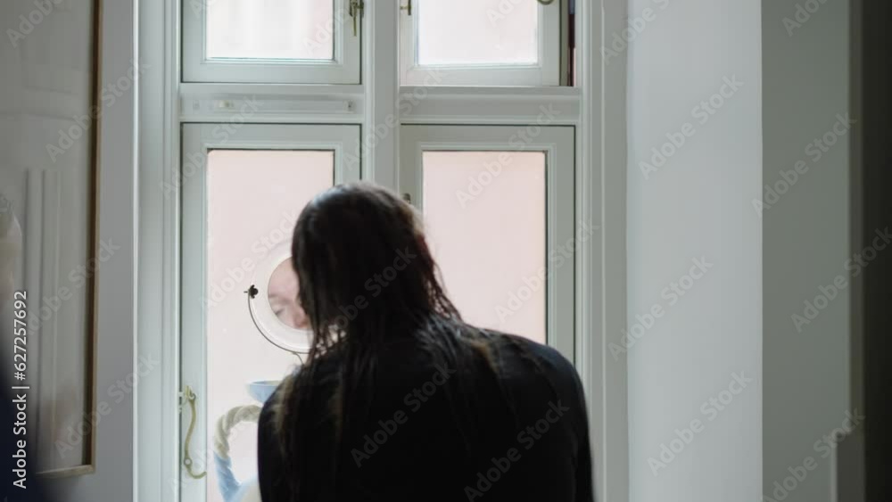 Graceful morning routine of a 37-year-old Caucasian woman, filmed from behind. With skillful precision, she applies eye makeup, enhancing her natural beauty, as seen in her little makeup mirror Graceful morning routine of a 37-year-old Caucasian woman, filmed from behind. With skillful precision, she applies eye makeup, enhancing her natural beauty, as seen in her little makeup mirror