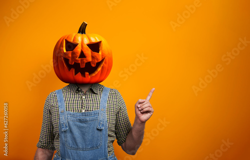 Fototapeta Person in Halloween costume of scarecrow with Jack-o'-lantern pumpkin head point
