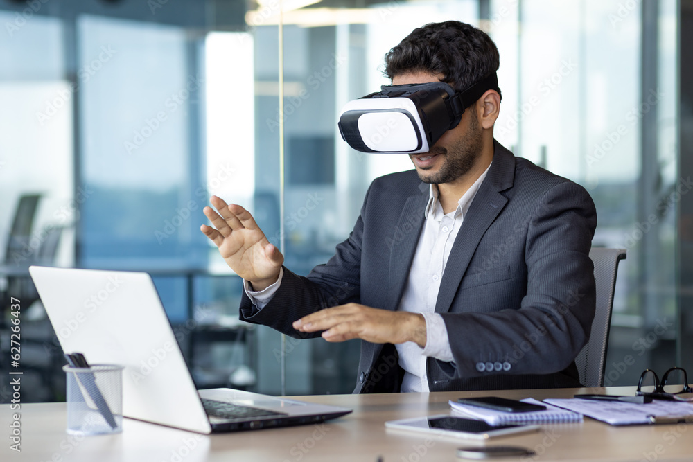 Obraz premium Businessman using vr glasses to view educational material and financial documents, graphs and tables online, financier inside office at workplace.