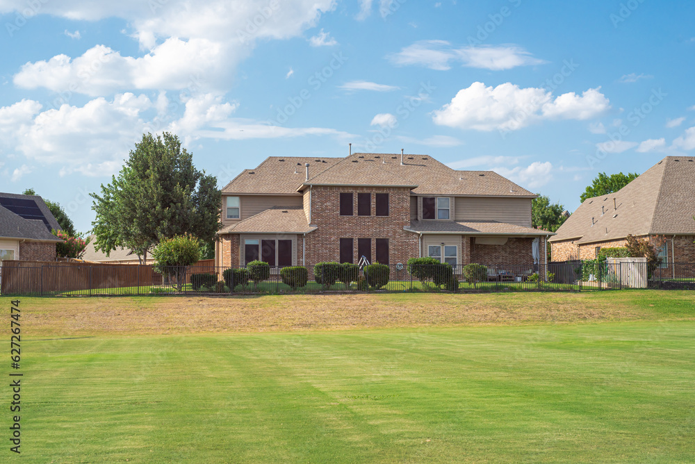Large grassy and rolling lawn of suburban park next to upscale residential neighborhood row of two-story houses in Flower Mound, Texas, USA Large grassy and rolling lawn of suburban park next to upscale residential neighborhood row of two-story houses in Flower Mound, Texas, USA