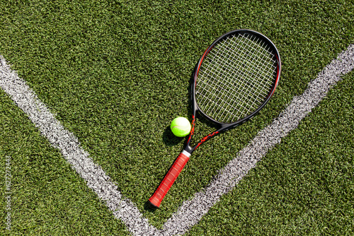 professional tennis racket with ball lies on green court, tennis equipment on the floor © Богдан Маліцький