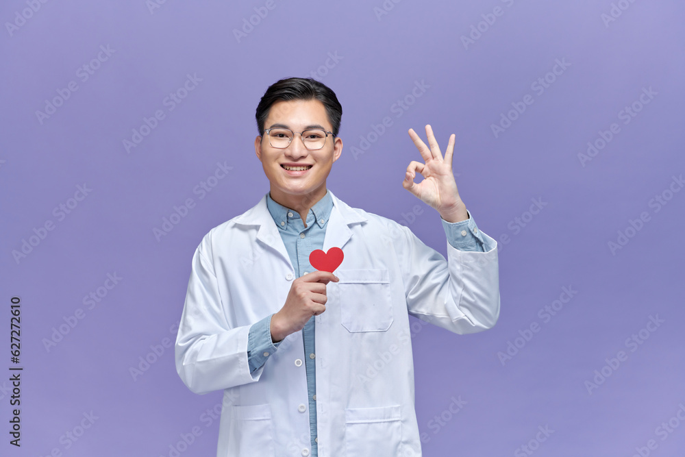 doctor holding red heart shape agains purple background doctor holding red heart shape agains purple background