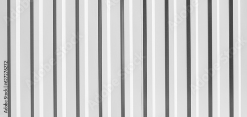 Corrugated metal fence. Metal profile fence in black and white. Texture of ribbed metal, sheets.