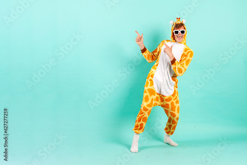 young funny guy in orange giraffe pajamas dances at party in sunglasses and points back photo