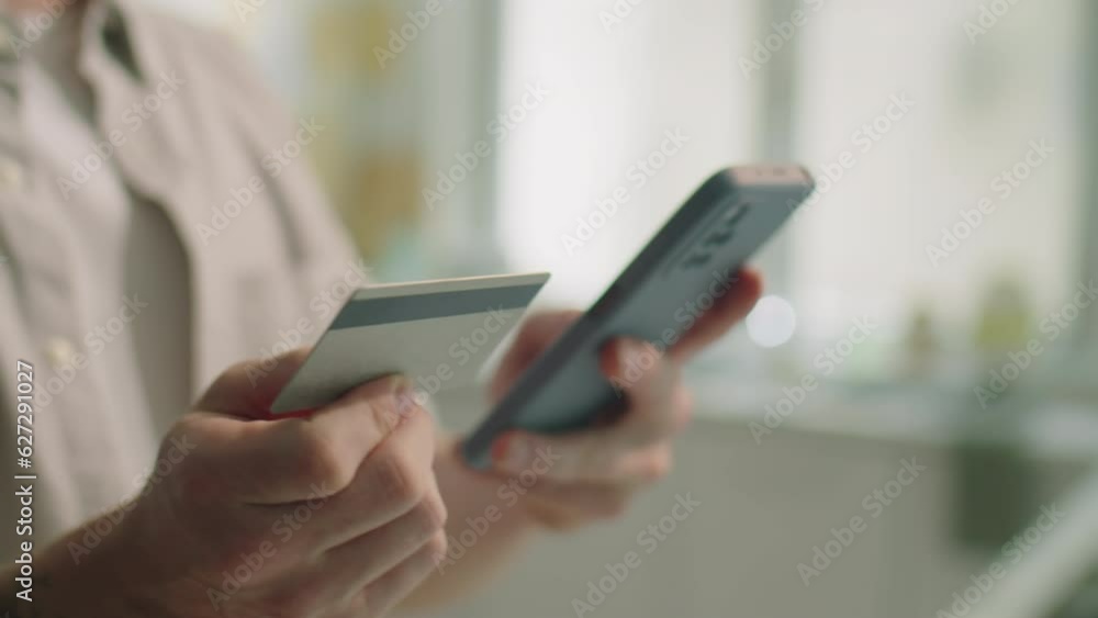 Close up shot of hands of man holding credit card and typing its details on smartphone while doing online shopping with mobile app Close up shot of hands of man holding credit card and typing its details on smartphone while doing online shopping with mobile app