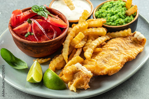 fish and chips served with mashed peas, vegetable salad, tartar sauce, traditional English dish photo