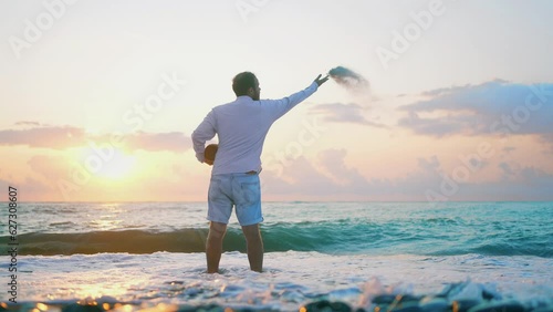 an unrecognizable man scatters ashes over the sea from a cremation urn