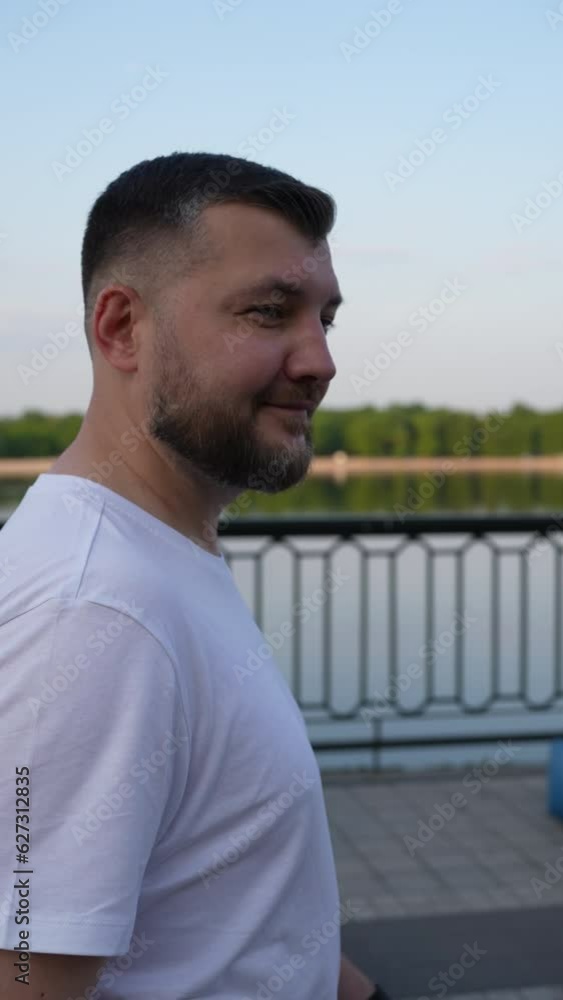 Handsome man in white t-shirt leisurely walking along the promenade, basking in the moment, while individuals relaxing comfortably on armchair bags. Handsome man in white t-shirt leisurely walking along the promenade, basking in the moment, while individuals relaxing comfortably on armchair bags.