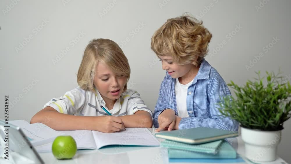 Primary elementary middle school boy girl siblings studying at desk table, writing in book and tablet at class home homework acquiring information knowledge Back to school. Primary elementary middle school boy girl siblings studying at desk table, writing in book and tablet at class home homework acquiring information knowledge Back to school.