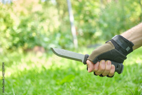 tactical military knife in gloved hand outdoors