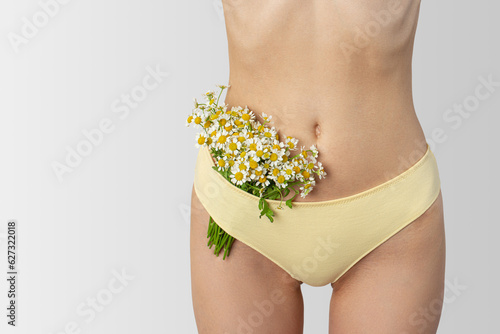 Daisies in women's hands and underwear. The concept of female intimate hygiene and health, naturalness.