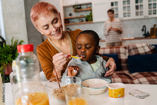 Mature white woman feeding her adopted child at home