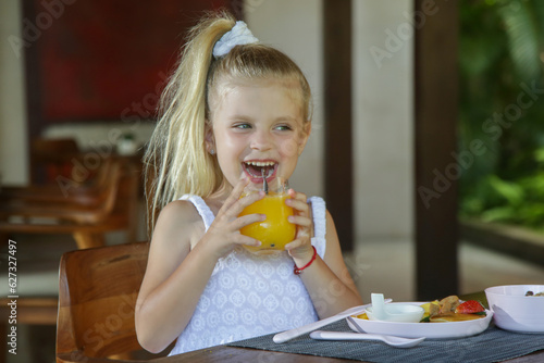 Adorable 5 years old girl having breakfast in the restaurant 