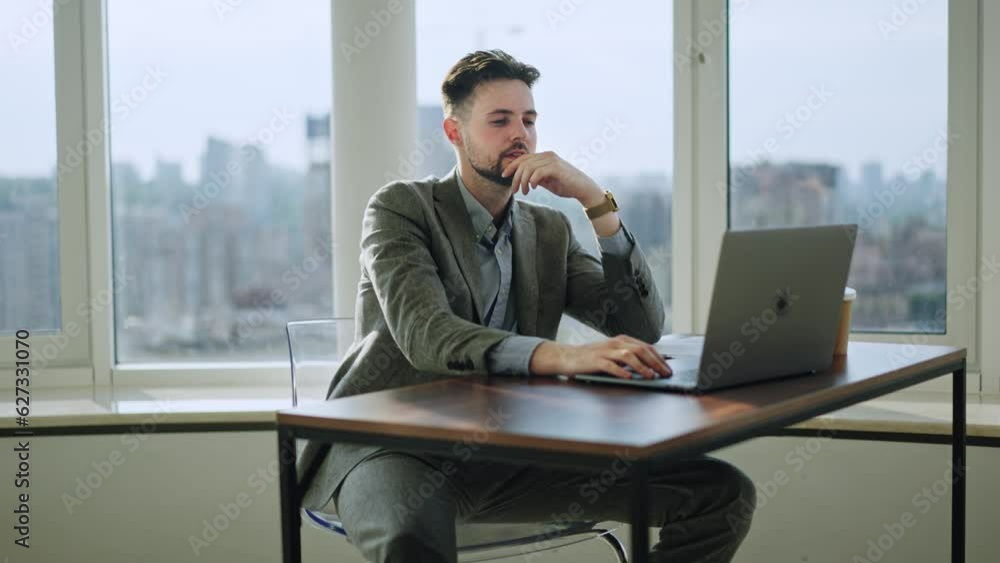 Young businessman working in an office space. Focused young man typing on a laptop. Steadycam shot. Concept of worker in Technology. Look at notifications on phone Young businessman working in an office space. Focused young man typing on a laptop. Steadycam shot. Concept of worker in Technology. Look at notifications on phone