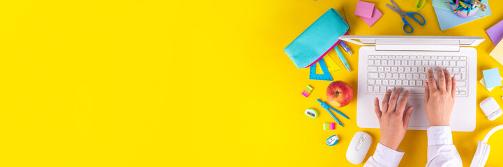Back to school, online education high-colored bright yellow background. White laptop with school education supplies, headphones, pencil case and accessories top view flat lay copy space
