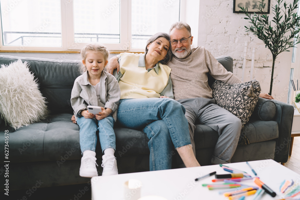 Senior man and woman resting on couch with kid