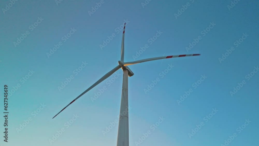 Rotating windmill turbine on clear blue sky background producing renewable green energy on wind farm Rotating windmill turbine on clear blue sky background producing renewable green energy on wind farm