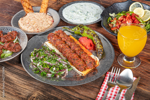 Grilled Turkish Adana, Urfa Kebab with grilled vegetables, onion and rice on plate. Adana durum.